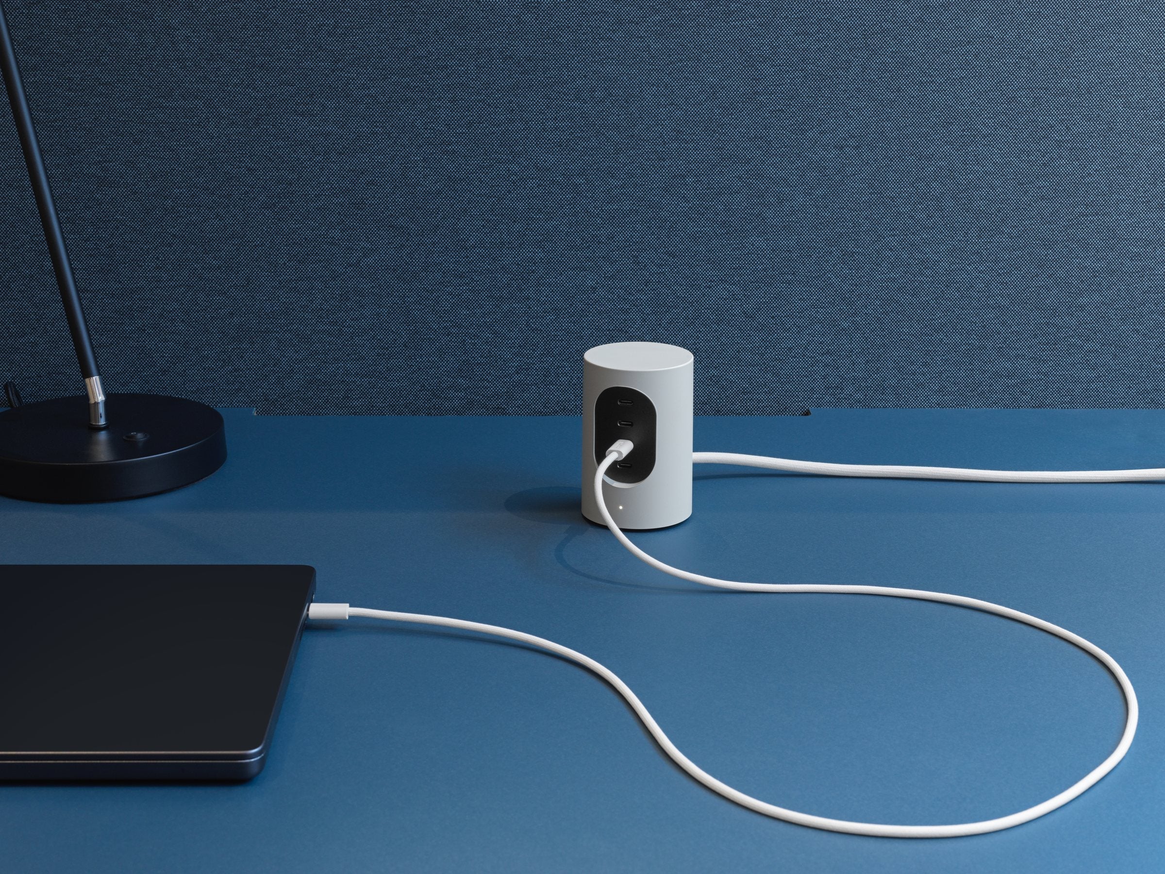 Cords® Cylindric UX1 in Mist White charging a laptop on a blue desk