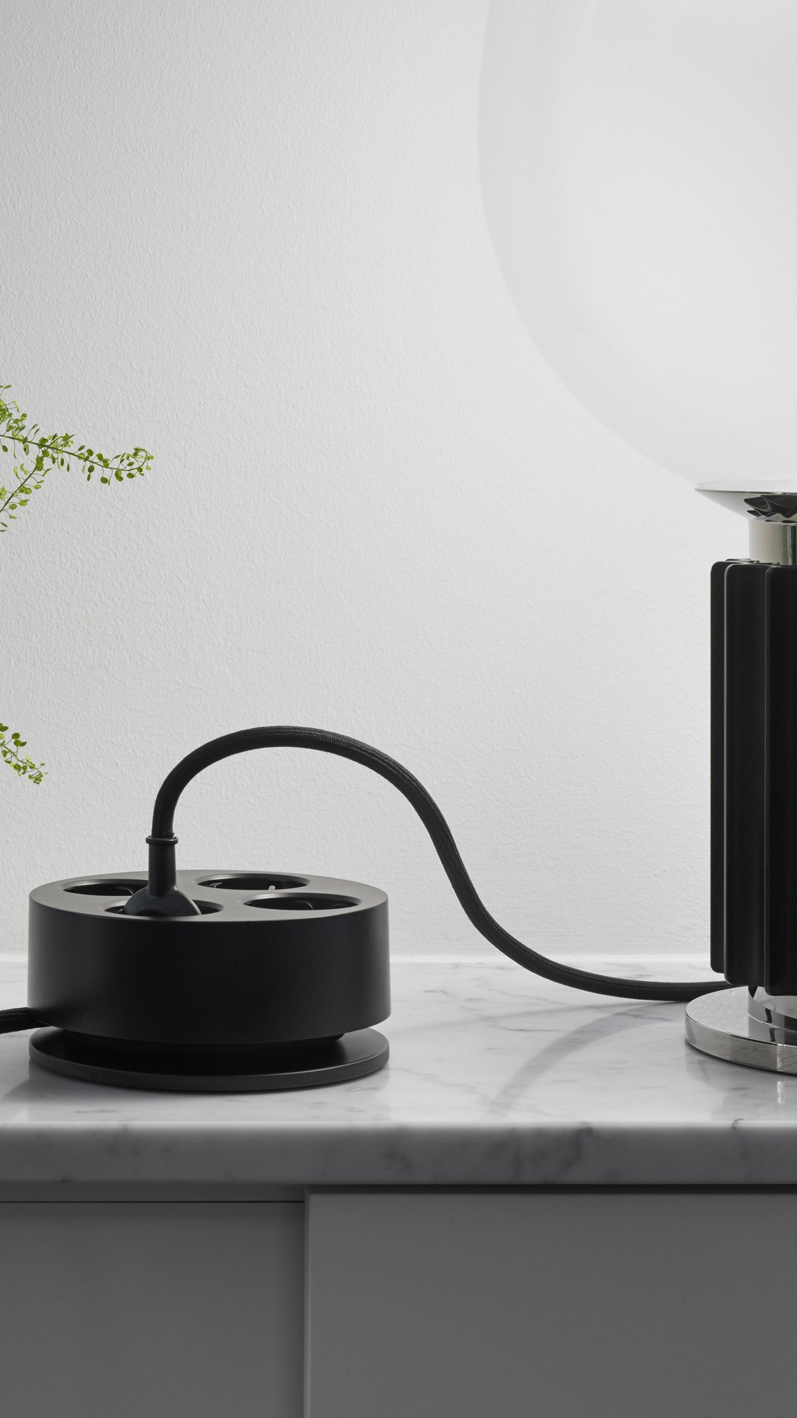 Cords Circular C2 in Jet Black beside a table lamp
